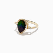The 14K Yellow Gold Ammolite and Diamond Ring features a large pear-shaped ammolite center, a diamond halo, and additional baguette diamonds set along the band.