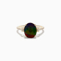 The 14K Yellow Gold Ammolite and Diamond Ring features a large oval faceted ammolite with dark green and red hues, flanked by two small rectangular stones and a band adorned with small sparkling diamonds.