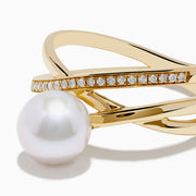 The 14K Yellow Gold Fresh Water Pearl and Diamond Crossover Ring showcases a crisscross design—one band set with sparkling diamonds, the other plain—topped with a luminous fresh water pearl at the center.