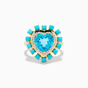 The 14K Yellow Gold Blue Topaz, Turquoise and Diamond Heart Cocktail Ring features a striking heart-shaped blue topaz center, surrounded by a halo of diamonds and an outer border of vibrant round turquoise stones.