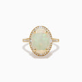 The 14K Yellow Gold Opal and Diamond Halo Cocktail Ring showcases an oval opal centerpiece encircled by a shimmering diamond halo, set against a white background.