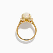 The 14K Yellow Gold Opal and Diamond Halo Cocktail Ring showcases an oval opal centerpiece encircled by a shimmering diamond halo, set against a white background.