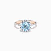 The Aquarius 14K Rose and White Gold Aquamarine and Diamond Ring features a large round aquamarine center, surrounded by a halo of sparkling diamonds with additional diamonds along the band.