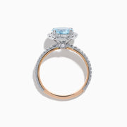 The Aquarius 14K Rose and White Gold Aquamarine and Diamond Ring features a large round aquamarine center, surrounded by a halo of sparkling diamonds with additional diamonds along the band.