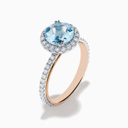 The Aquarius 14K Rose and White Gold Aquamarine and Diamond Ring features a large round aquamarine center, surrounded by a halo of sparkling diamonds with additional diamonds along the band.