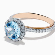 The Aquarius 14K Rose and White Gold Aquamarine and Diamond Ring features a large round aquamarine center, surrounded by a halo of sparkling diamonds with additional diamonds along the band.