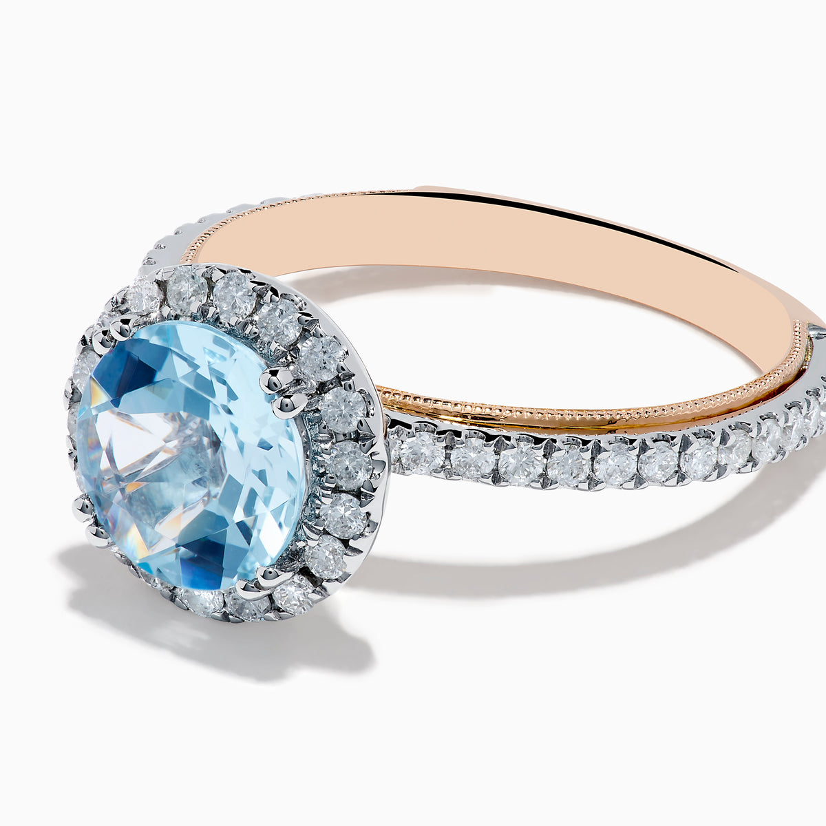 The Aquarius 14K Rose and White Gold Aquamarine and Diamond Ring features a large round aquamarine center, surrounded by a halo of sparkling diamonds with additional diamonds along the band.