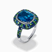 The 925 Sterling Silver Blue Topaz Cushion Multi Gemstone Halo Ring features a large rectangular blue topaz center, encircled by a halo of small white, green, and blue stones.