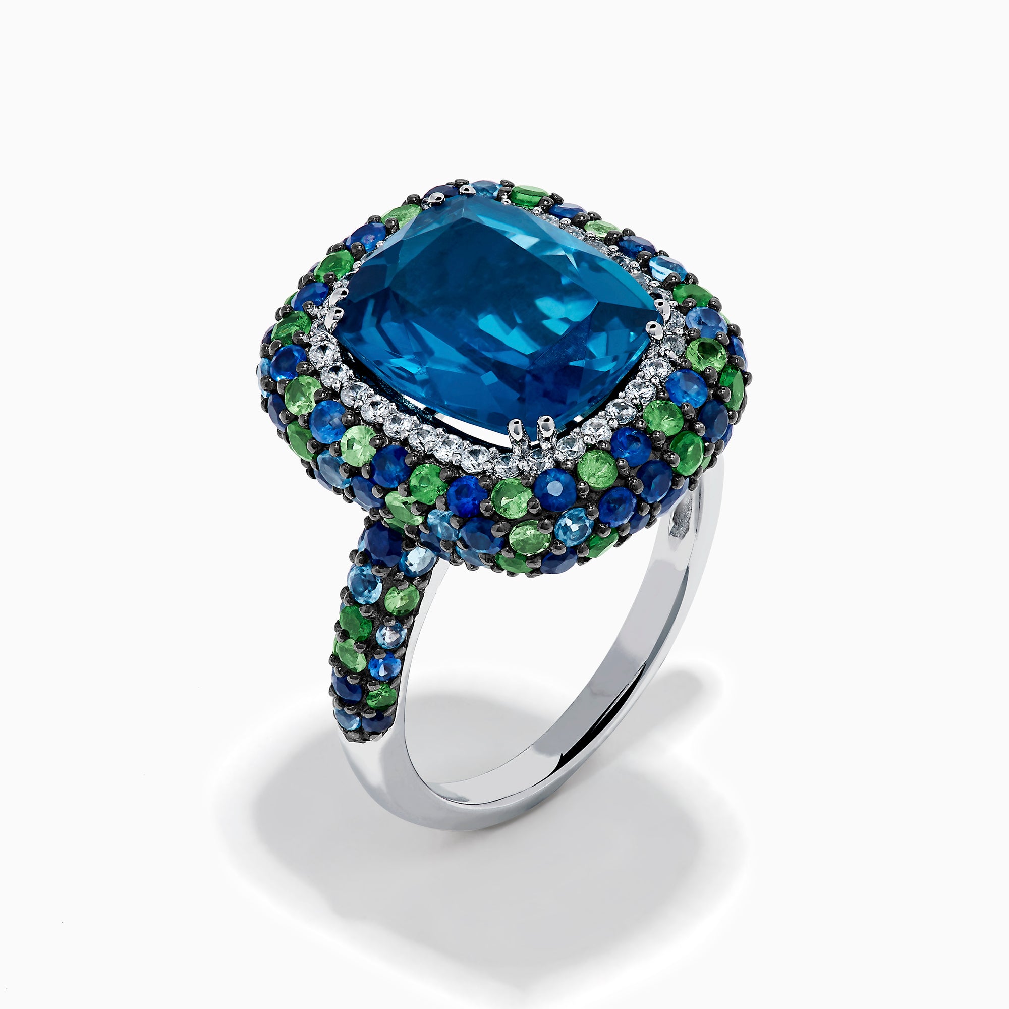 The 925 Sterling Silver Blue Topaz Cushion Multi Gemstone Halo Ring features a large rectangular blue topaz center, encircled by a halo of small white, green, and blue stones.