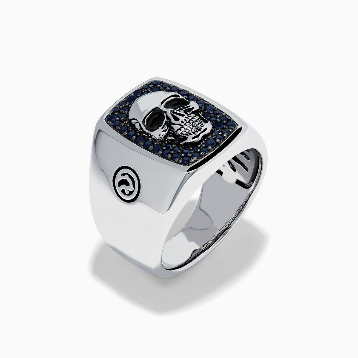 The Men's Sterling Silver Black Spinel Skull Ring features a central raised skull, small black spinel stones surrounding it, and circular engraved symbols on each side of the band.