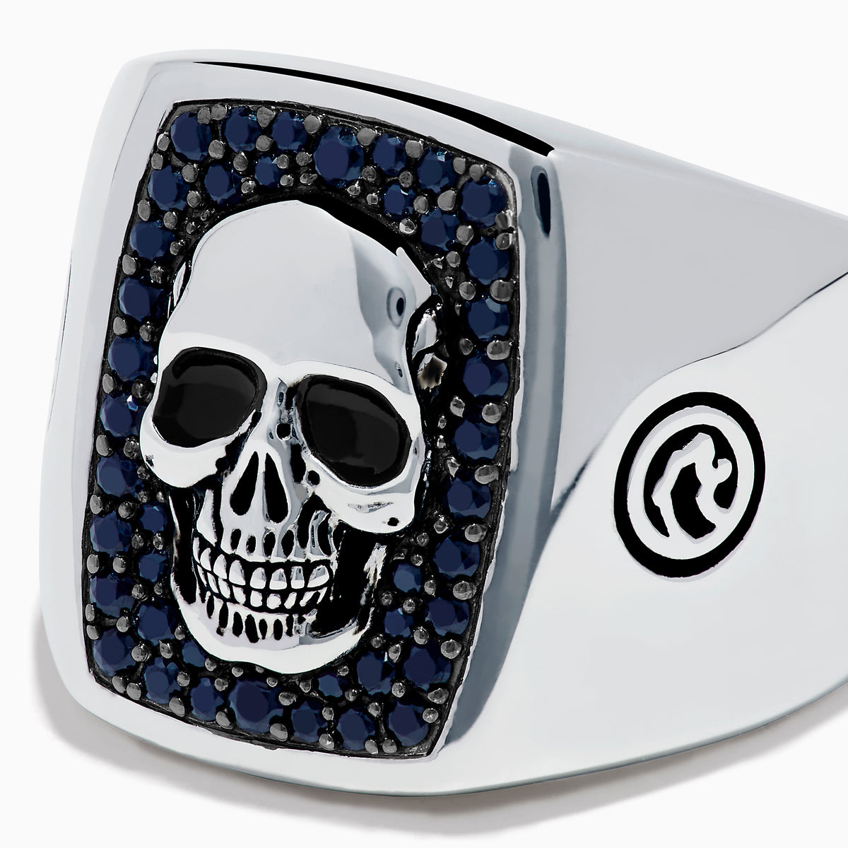 The Men's Sterling Silver Black Spinel Skull Ring features a central raised skull, small black spinel stones surrounding it, and circular engraved symbols on each side of the band.