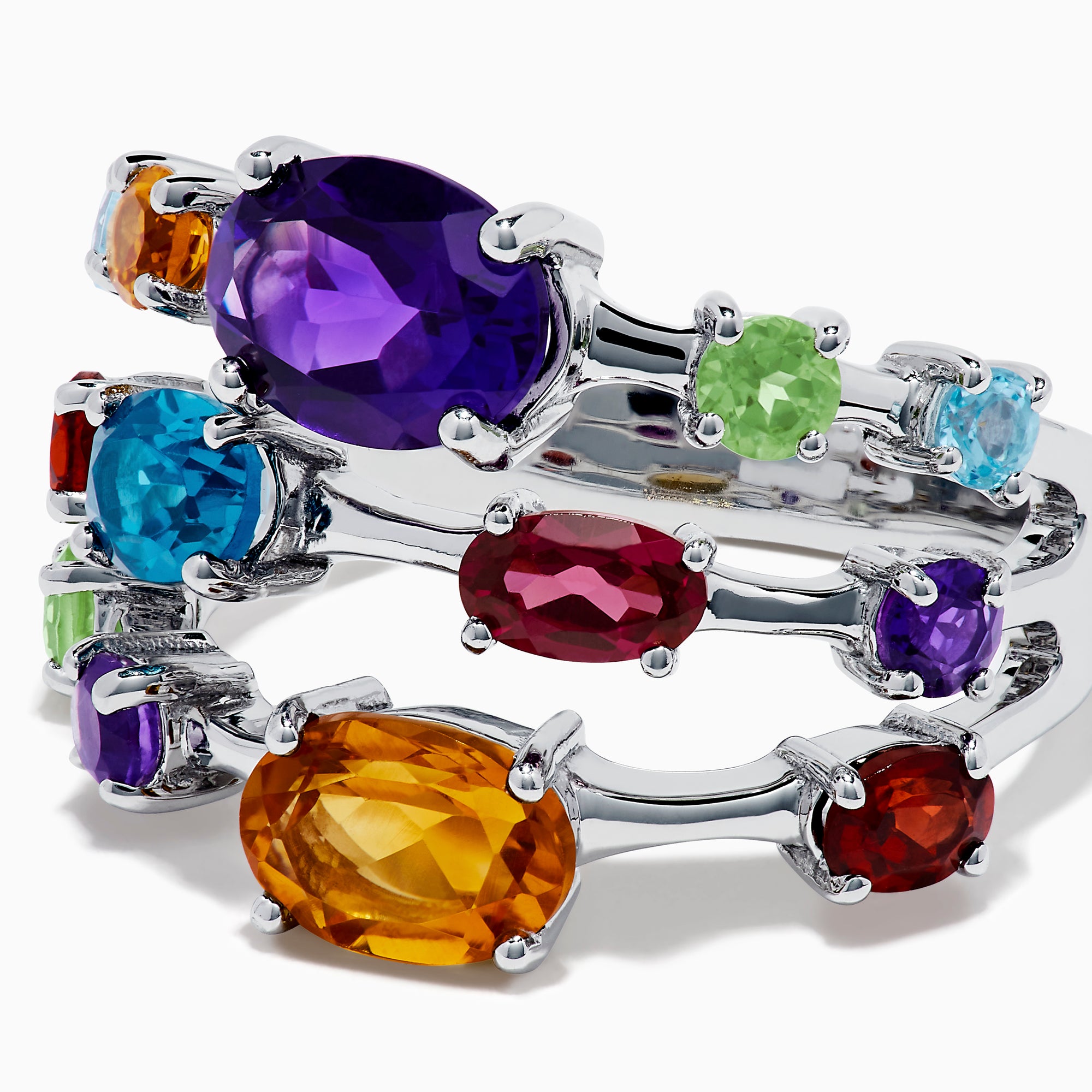 The 925 Sterling Silver Multi Color Gemstone 3 Row Band showcases three stacked rings with vibrant purple, blue, green, orange, and red gemstones set on a sleek silver background.