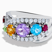 The Mosaic 925 Sterling Silver Multi Color Gemstone Ring features a row of red, green, yellow, purple, and blue gemstones accented by clear stones surrounding the band.