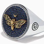 The Men's Sterling Silver Black Spinel Moth Ring showcases a gold moth and crescent moon on a round navy face, accented with sparkling black spinel stones.