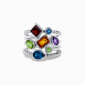 The Mosaic 925 Sterling Silver Multi Gemstone Ring showcases colorful blue, green, red, orange, and purple gemstones in various shapes on intertwined sterling silver bands.