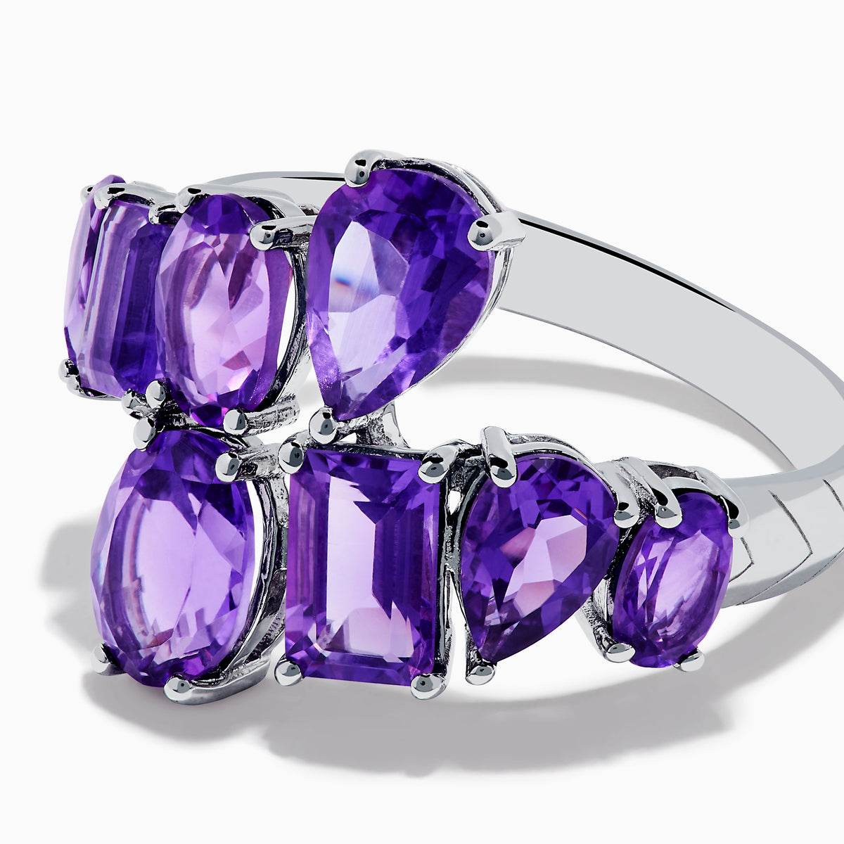 The 925 Sterling Silver Amethyst Bypass Ring showcases seven faceted purple gemstones of assorted shapes and sizes set in a sleek, modern open design against a plain white background.