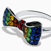 The Safari 925 Sterling Silver Multi Color Sapphire Bow Ring features red, yellow, green, and blue sapphires arranged symmetrically in a bow design against a white background.