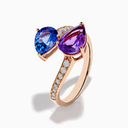 The 14K Rose Gold Amethyst, Tanzanite and Diamond Ring showcases a modern open band set with pear-shaped blue tanzanite, purple amethyst, and small round diamonds for an elegant look.