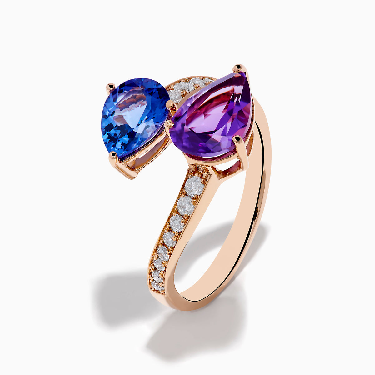 The 14K Rose Gold Amethyst, Tanzanite and Diamond Ring showcases a modern open band set with pear-shaped blue tanzanite, purple amethyst, and small round diamonds for an elegant look.