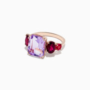 A 14K Rose Gold ring featuring a large rectangular Amethyst center stone, flanked by two oval Rhodolite and two round Pink Tourmaline gemstones, set against a white background.