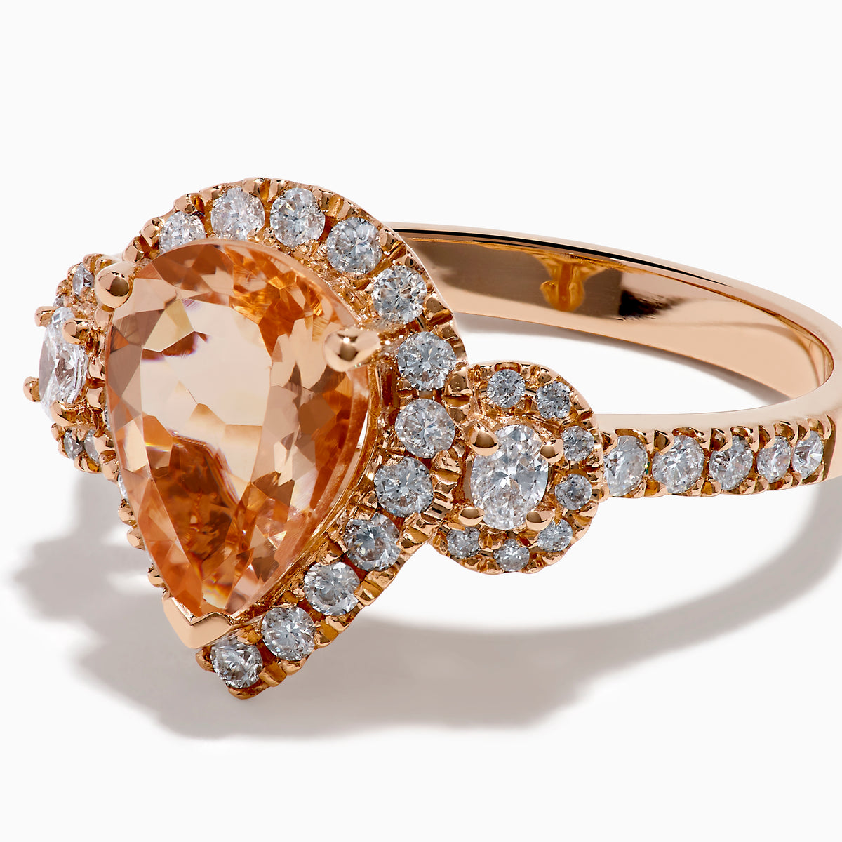 The 14K Rose Gold Pear Morganite and Diamond Halo Ring showcases a peach-hued pear morganite with sparkling diamond halo and accents, all set in 14K rose gold, against a white background.