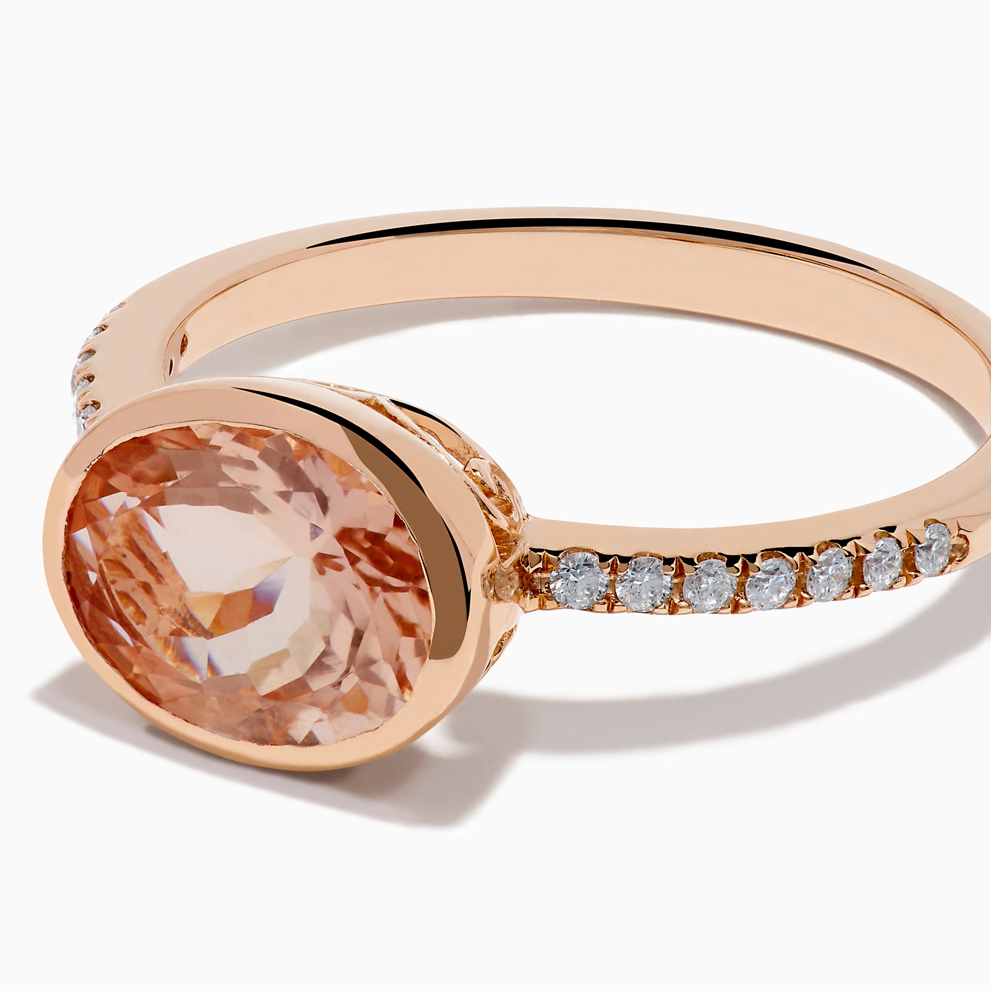 The 14K Rose Gold Morganite and Diamond East West Bezel Ring showcases a striking round peach morganite center stone with small diamonds along the band, set against a white background.