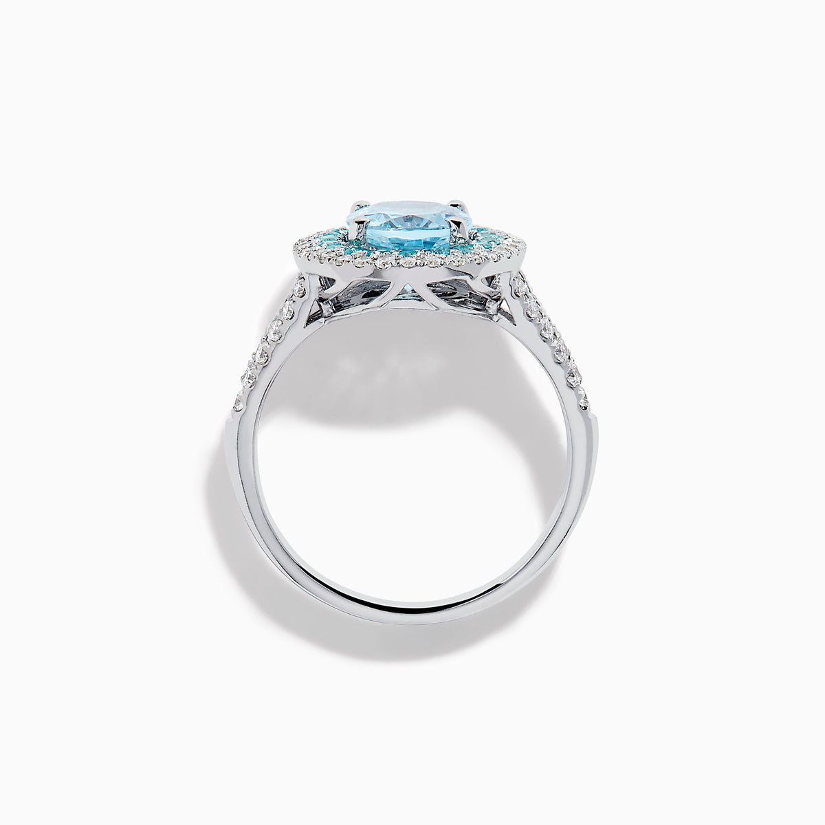 The Aquarius 14K White Gold Aquamarine, Paraiba, and Diamond Ring features an oval aquamarine center stone encircled by two halos of sparkling blue Paraiba and clear diamonds, displayed on a plain white background.