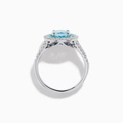 The Aquarius 14K White Gold Aquamarine, Paraiba, and Diamond Ring features an oval aquamarine center stone encircled by two halos of sparkling blue Paraiba and clear diamonds, displayed on a plain white background.