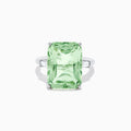 A 14K White Gold Green Amethyst and Diamond 3-Stone Ring features a rectangular, faceted green amethyst center with two small side diamonds, set in white gold and displayed against a white background.