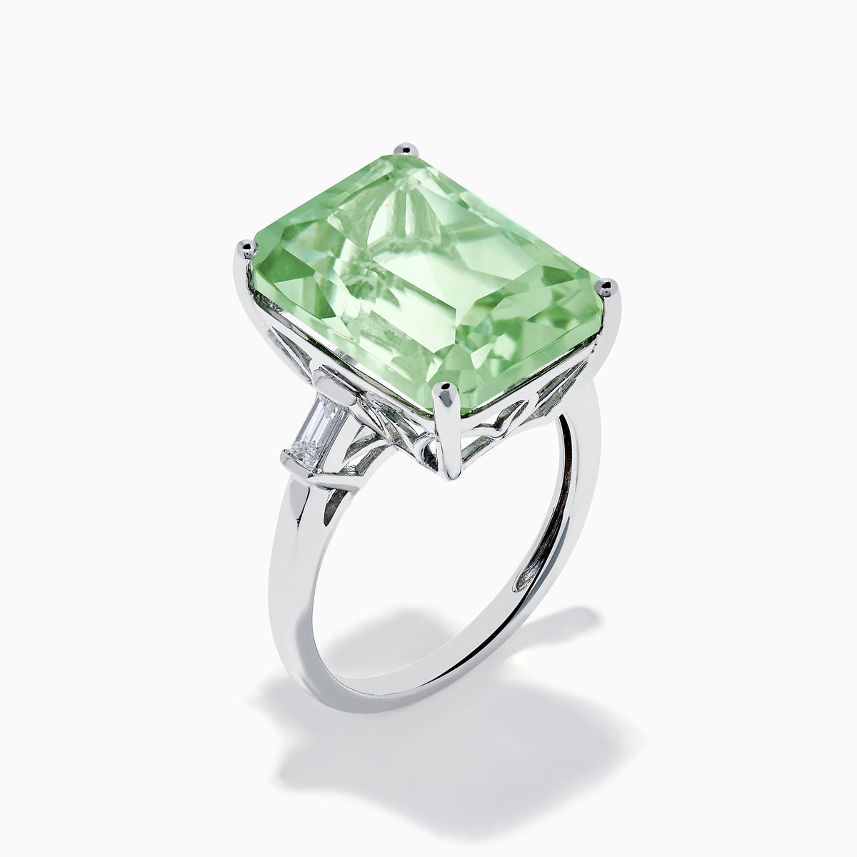 A 14K White Gold Green Amethyst and Diamond 3-Stone Ring features a rectangular, faceted green amethyst center with two small side diamonds, set in white gold and displayed against a white background.