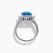 The Ocean Bleu 14K White Gold Blue Topaz and Diamond Halo Ring features a large cushion-cut blue topaz center stone, surrounded by a sparkling halo of baguette-shaped diamonds, all set in elegant white gold.