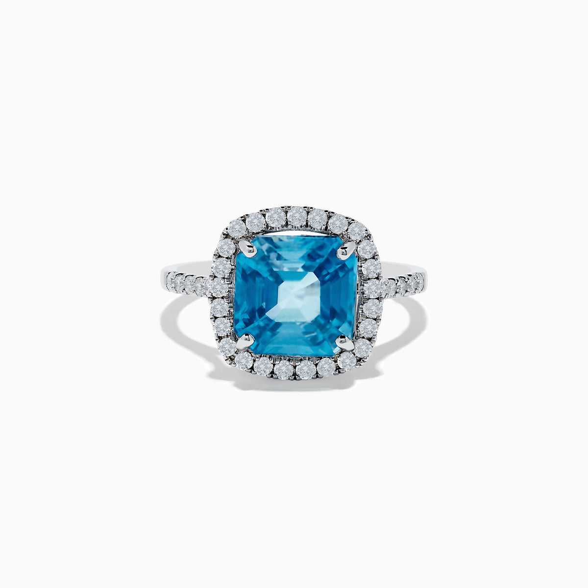 The 14K White Gold Blue Zircon and Diamond Ring showcases a large cushion-cut blue zircon center, surrounded by a halo of small round diamonds on the setting and band, set against a white background.
