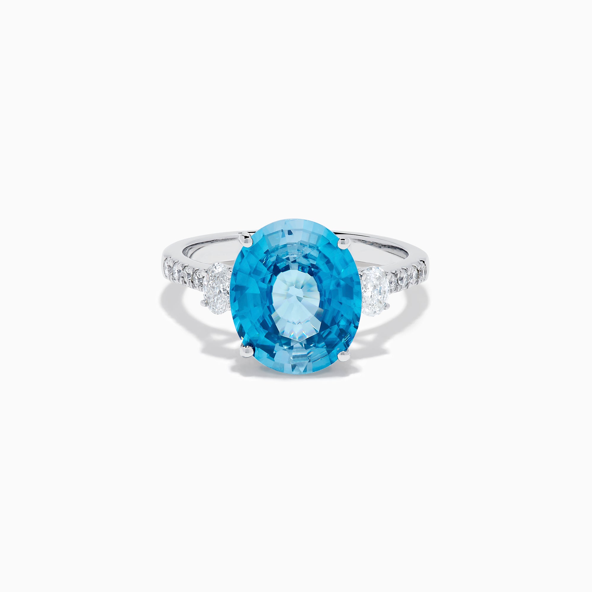 The 14K White Gold Blue Zircon and Diamond 3 Stone Ring features a large oval blue zircon center stone with diamonds on each side, shown on a white background.