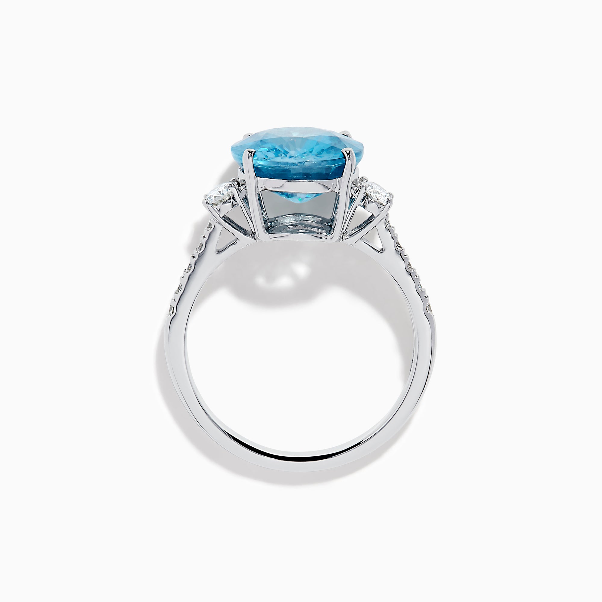 The 14K White Gold Blue Zircon and Diamond 3 Stone Ring features a large oval blue zircon center stone with diamonds on each side, shown on a white background.