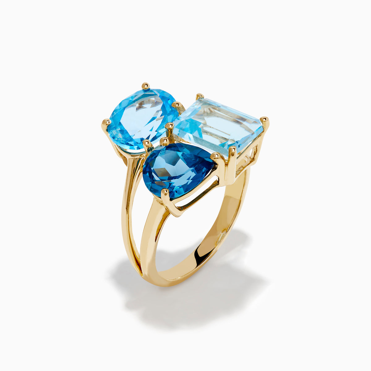 The 14K Yellow Gold London, Swiss & Sky Blue Cocktail Ring features three asymmetrically-clustered gemstones: an oval light blue, a round Swiss blue, and a rectangular light blue stone.