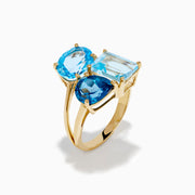 The 14K Yellow Gold London, Swiss & Sky Blue Cocktail Ring features three asymmetrically-clustered gemstones: an oval light blue, a round Swiss blue, and a rectangular light blue stone.