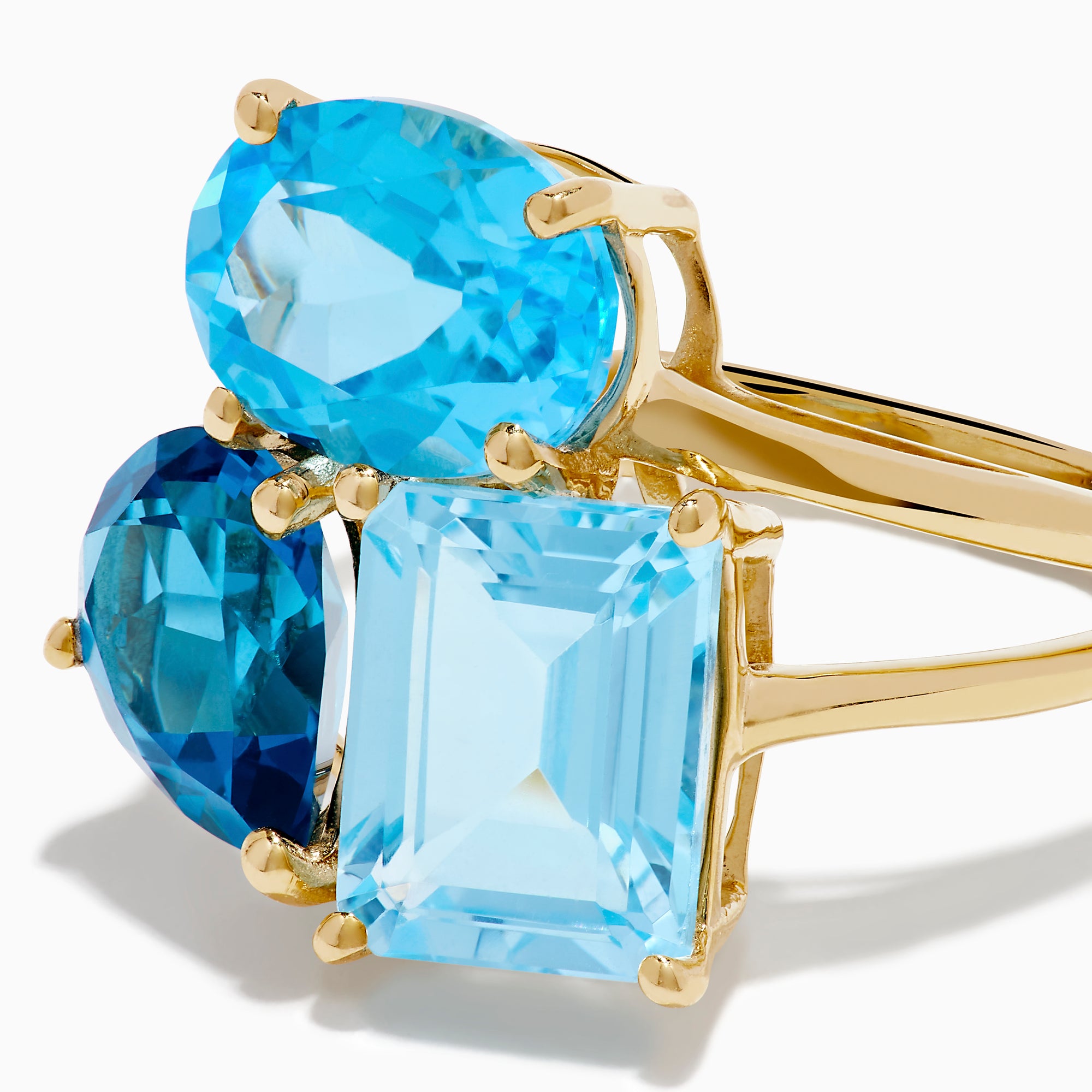 The 14K Yellow Gold London, Swiss & Sky Blue Cocktail Ring features three asymmetrically-clustered gemstones: an oval light blue, a round Swiss blue, and a rectangular light blue stone.