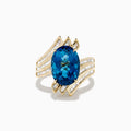 The Ocean Bleu 14K Yellow Gold London Blue Topaz and Diamond Ring showcases a large, oval London Blue Topaz center with sparkling diamond rows in a wavy, geometric design.