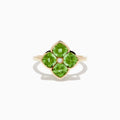 The 14K Yellow Gold Peridot and Diamond Ring displays a clover-shaped design with four faceted green peridots and a central round diamond, shown against a white background.