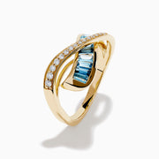 The Ocean Blue 14K Yellow Gold Blue Topaz and Diamond Criss Cross Ring features an infinity design: one band set with white diamonds, the other with rectangular blue topaz gemstones, shown on a white background.