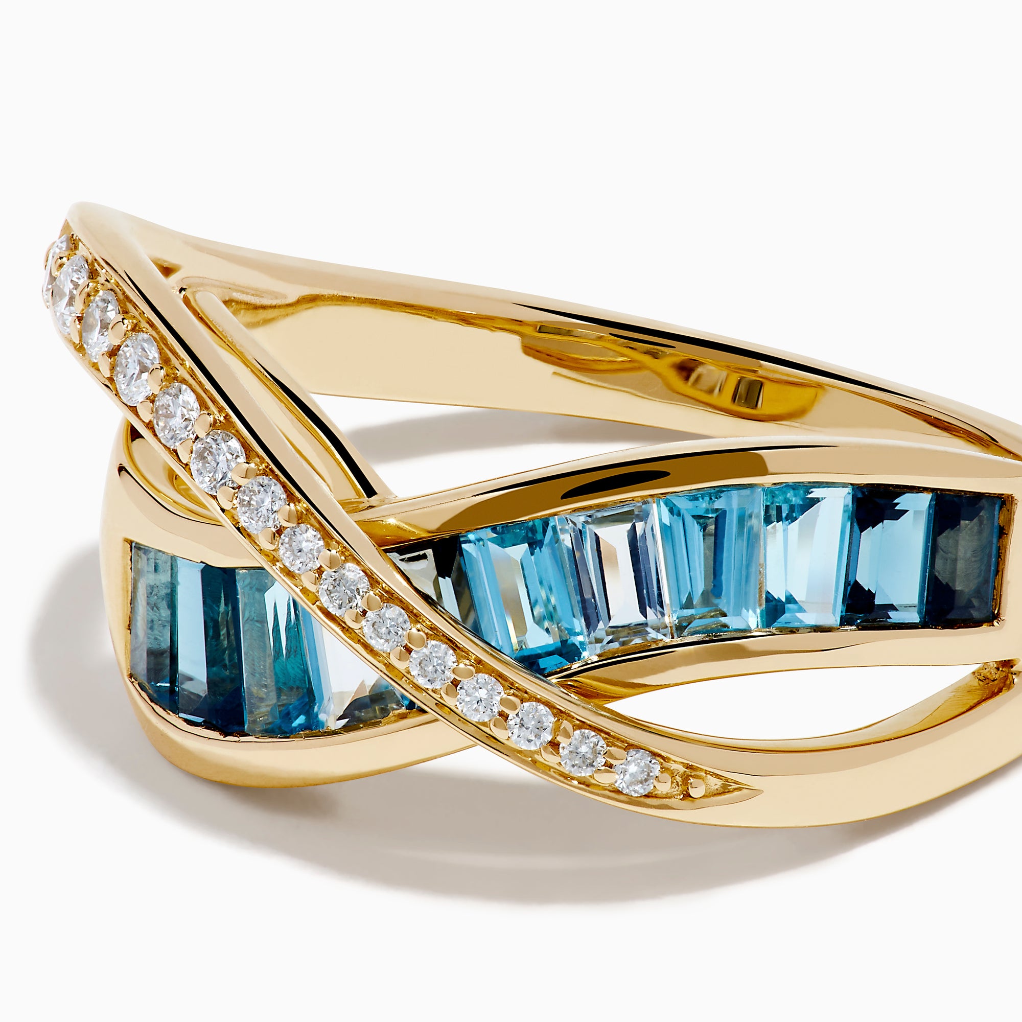 The Ocean Blue 14K Yellow Gold Blue Topaz and Diamond Criss Cross Ring features an infinity design: one band set with white diamonds, the other with rectangular blue topaz gemstones, shown on a white background.