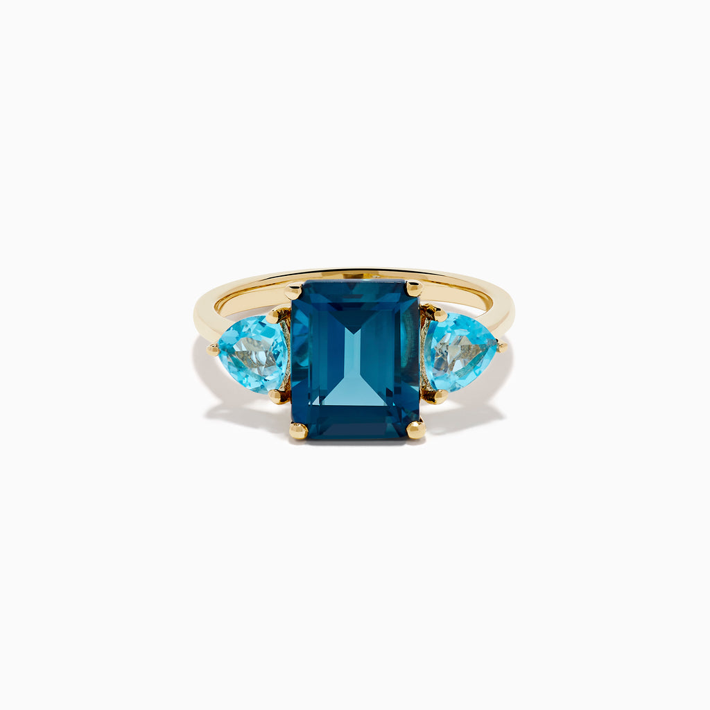The 14K Yellow Gold Sky Blue and London Blue Topaz 3 Stone Ring features a large rectangular blue topaz flanked by two heart-shaped stones, all set in yellow gold. A stunning piece for any occasion.