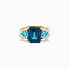 The 14K Yellow Gold Sky Blue and London Blue Topaz 3 Stone Ring features a large rectangular blue topaz flanked by two heart-shaped stones, all set in yellow gold. A stunning piece for any occasion.