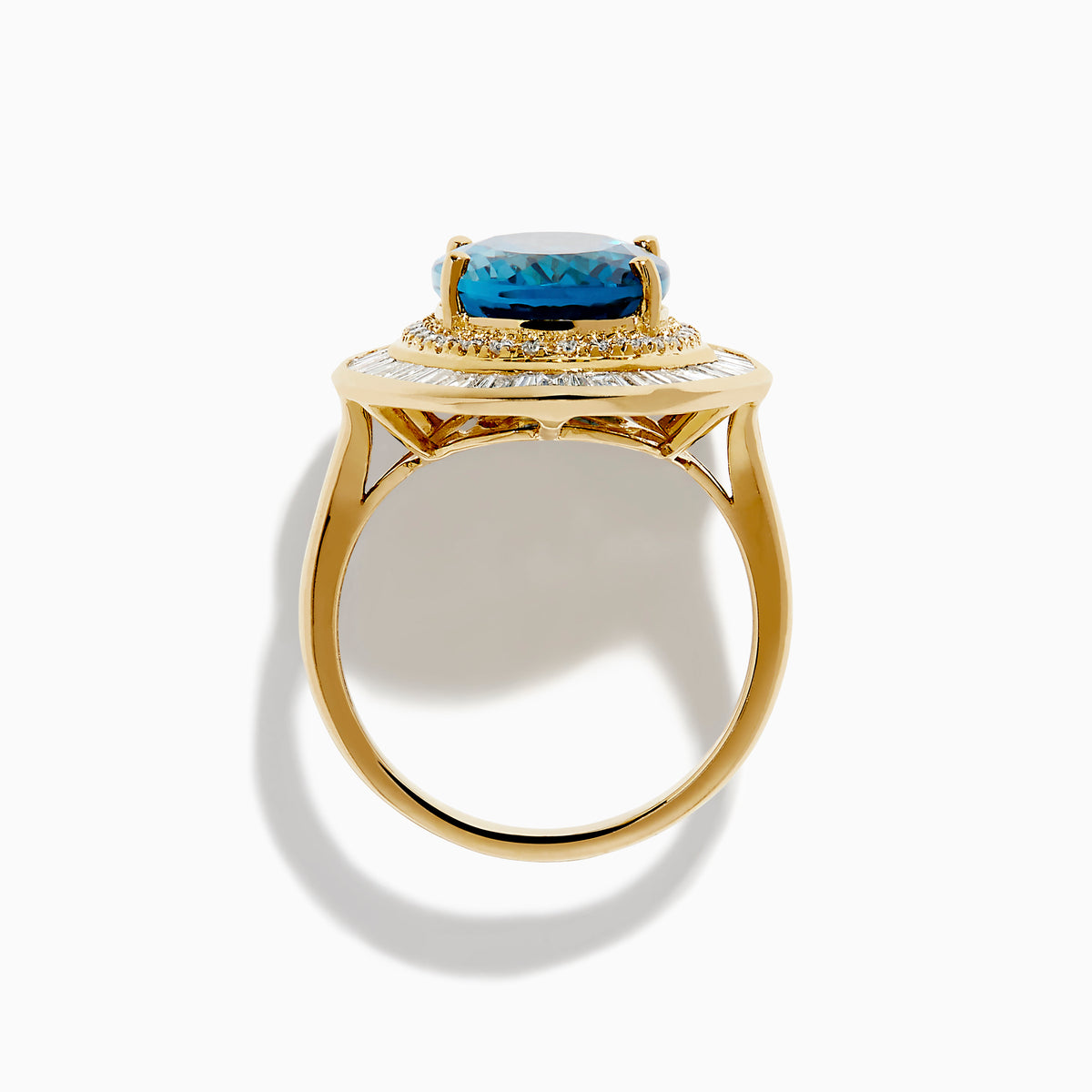 The 14K Yellow Gold London Blue Topaz and Diamond Double Halo Ring features an oval London Blue Topaz at the center, encircled by two halos of sparkling round and baguette-cut diamonds.