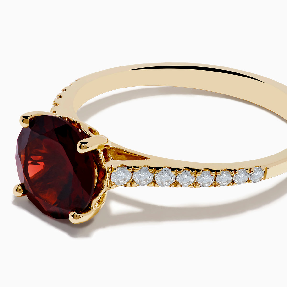 The 14K Yellow Gold Garnet and Diamond Ring features a large round deep red garnet center, accented by small white diamonds on each side of the band, displayed against a white background.