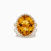 The Sunset 14K Yellow Gold Citrine and Diamond Halo Ring features a large oval citrine surrounded by sparkling diamonds, beautifully set against a plain white background.