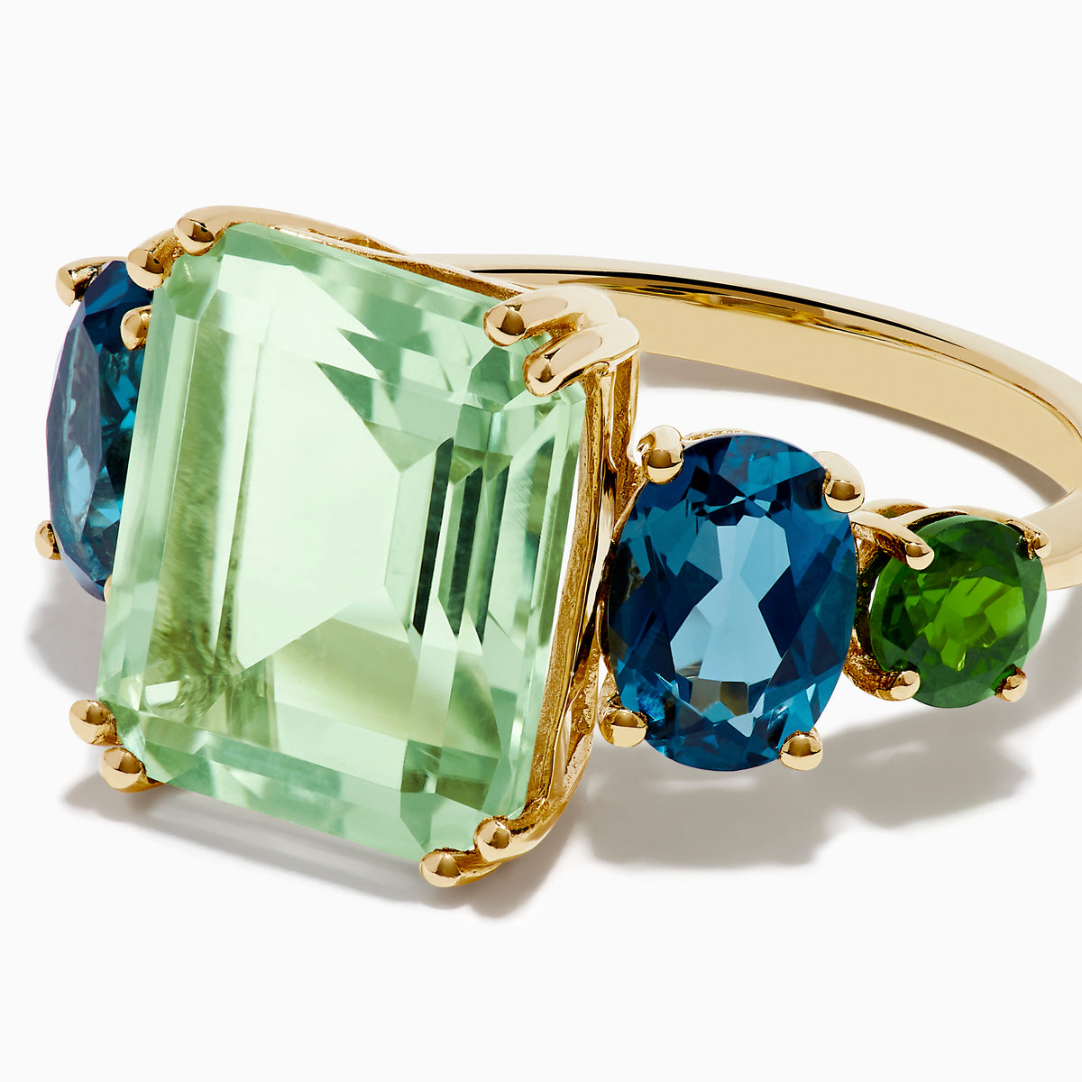 The 14K Yellow Gold Amethyst, Blue Topaz, and Chrome Diopside Cocktail Ring features a large rectangular amethyst center stone, flanked by two oval blue topaz and two smaller chrome diopside stones on each side.