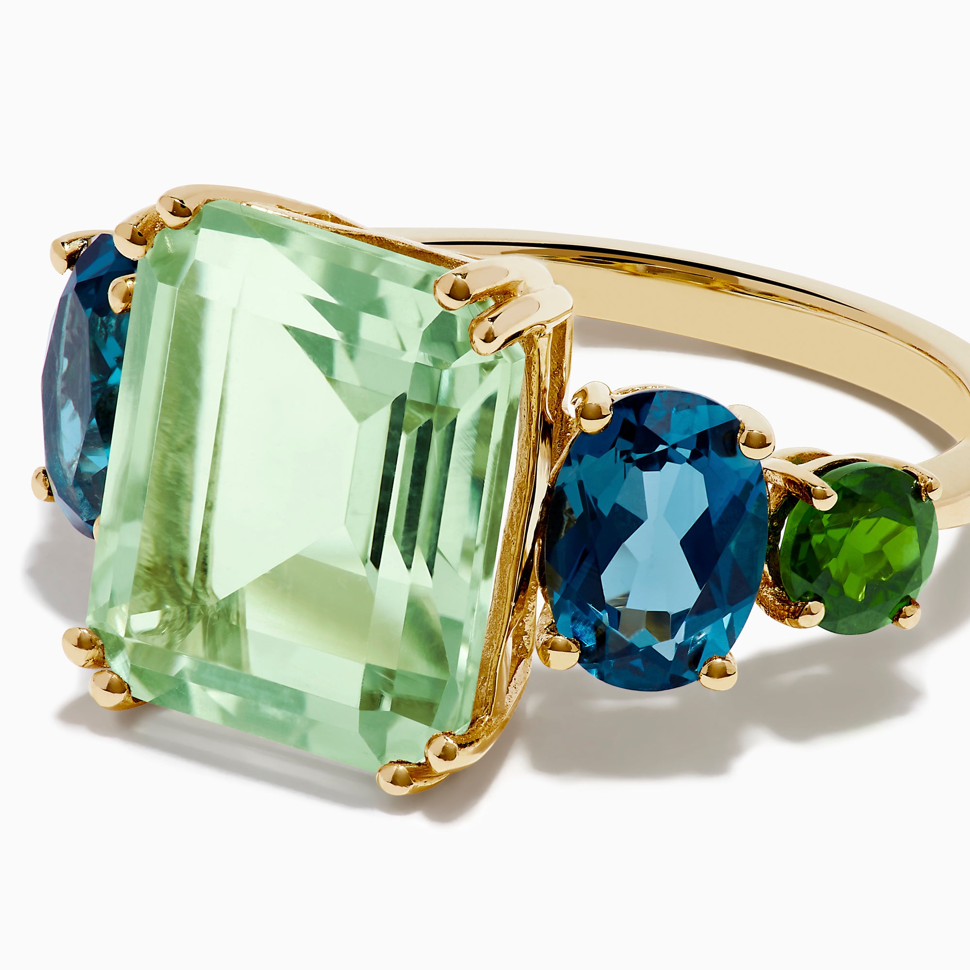 The 14K Yellow Gold Amethyst, Blue Topaz, and Chrome Diopside Cocktail Ring features a large rectangular amethyst center stone, flanked by two oval blue topaz and two smaller chrome diopside stones on each side.