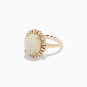 The Aurora 14K Yellow Gold Opal Diamond Ring showcases an oval opal center, encircled by a halo of baguette-cut diamonds, set against a white background.