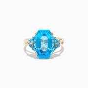 The Ocean Bleu 14K Yellow Gold Blue Topaz Ring showcases a large emerald-cut blue topaz, accented by two smaller matching stones, all set on a sleek, elegant gold band.